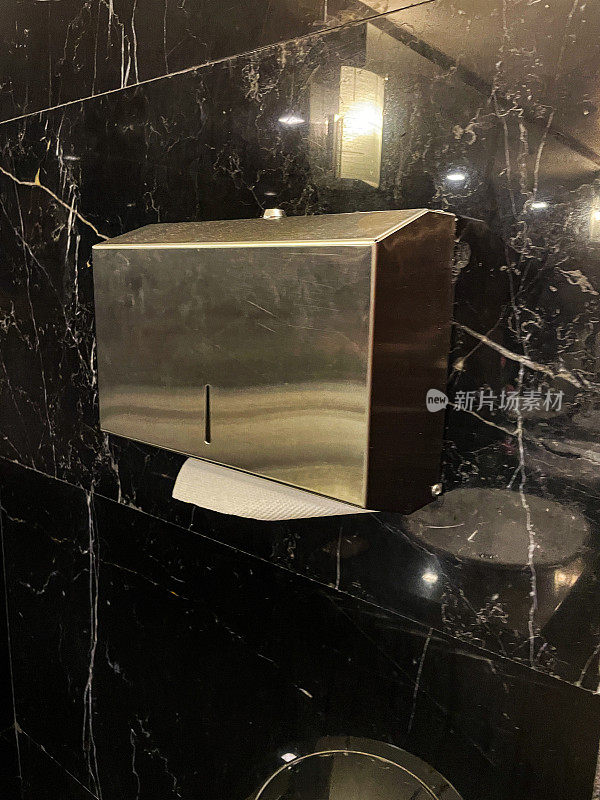 印度一家豪华酒店的公共厕所里的金属手巾/卫生纸自动售货机，黑色大理石墙壁和白纸